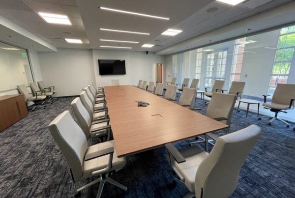 Renovated suite in Shelby with long conference table, chairs, and mounted monitor.