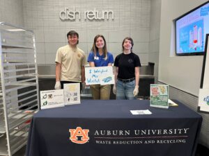 Event organizers standing at a table for the Weight Your Waste event.