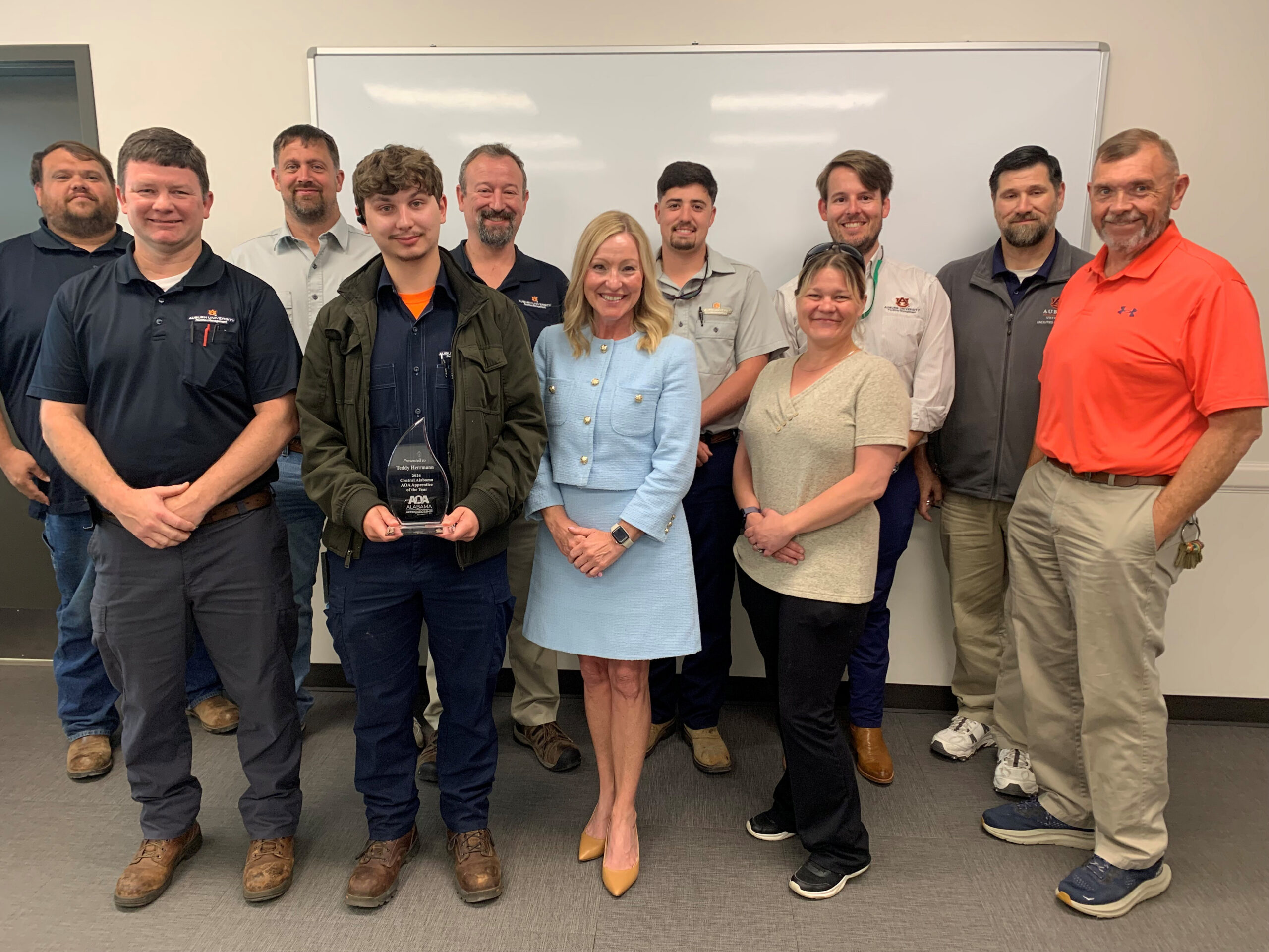 Facilities leadership recently gathered to recognize Teddy Hermann as the 2026 Alabama Office of Apprenticeship Apprentice of the Year. Pictured are Jonathan McDonald, Zone 1 assistant supervisor; Chris Potts, Zone 1 supervisor; Travis Herrmann, Zone 1 assistant supervisor; Cullen Kennedy, electrical apprentice III and 2025 Apprentice of the Year; Josh Conradson, director of Maintenance; Travis Tally, assistant director of Maintenance; Jeff Gulledge, assistant supervisor for Preventive Maintenance; Teddy Herrmann, HVACR apprentice III and 2026 Apprentice of the Year; Meredith Smith, director of the Alabama Office of Apprenticeship; Scooter Herrmann, Business and Administration IT; and Johnny McDonald, HVACR technical advisor.