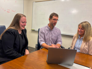 Hayley Caver - Dan Whatley - Loren Winn sit at desk.